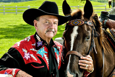 Alligator Ron standing next to his horse wearing his black cowboy hat